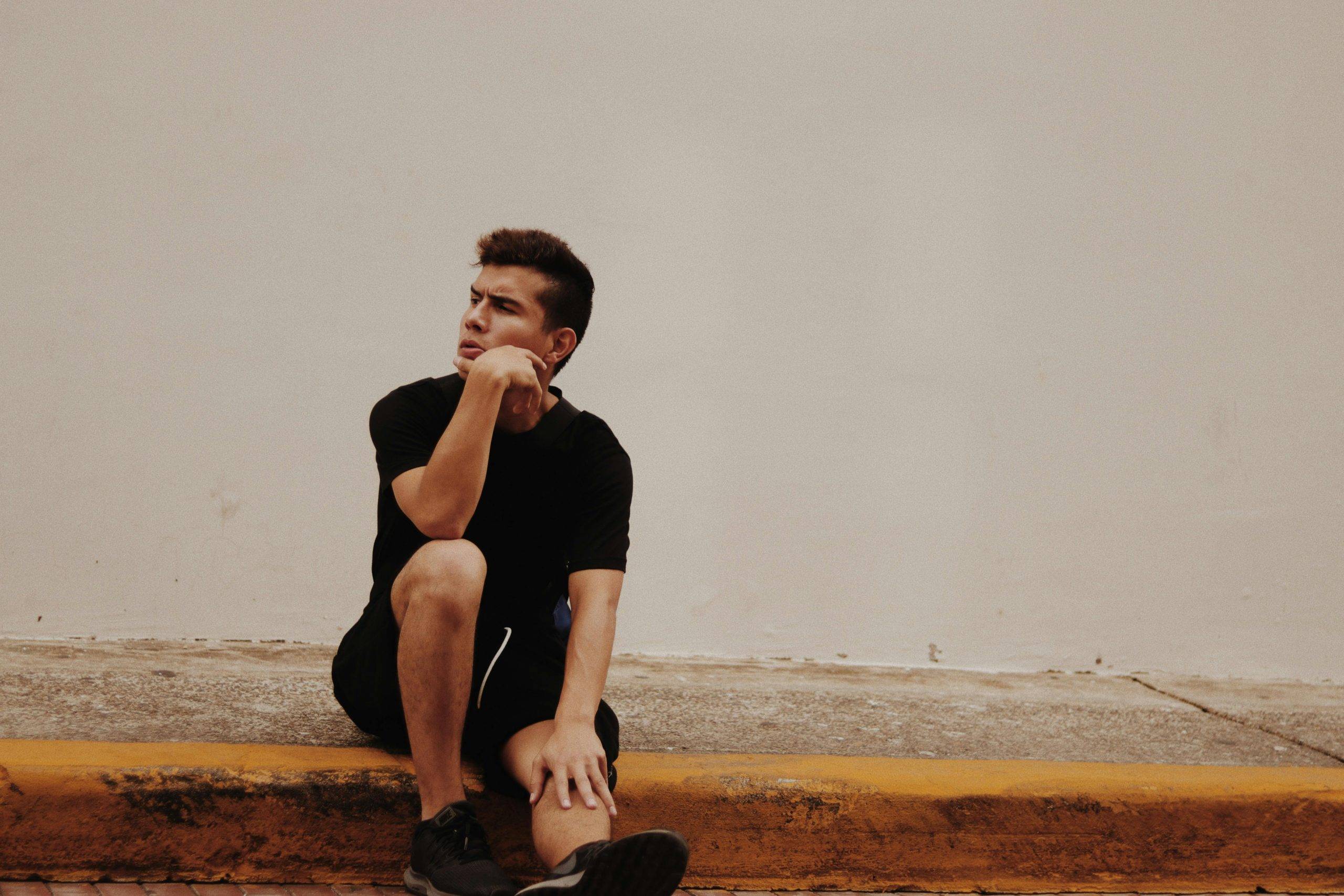 A man sitting, looking pensive and thinking, indicating thinking about better career decisions.