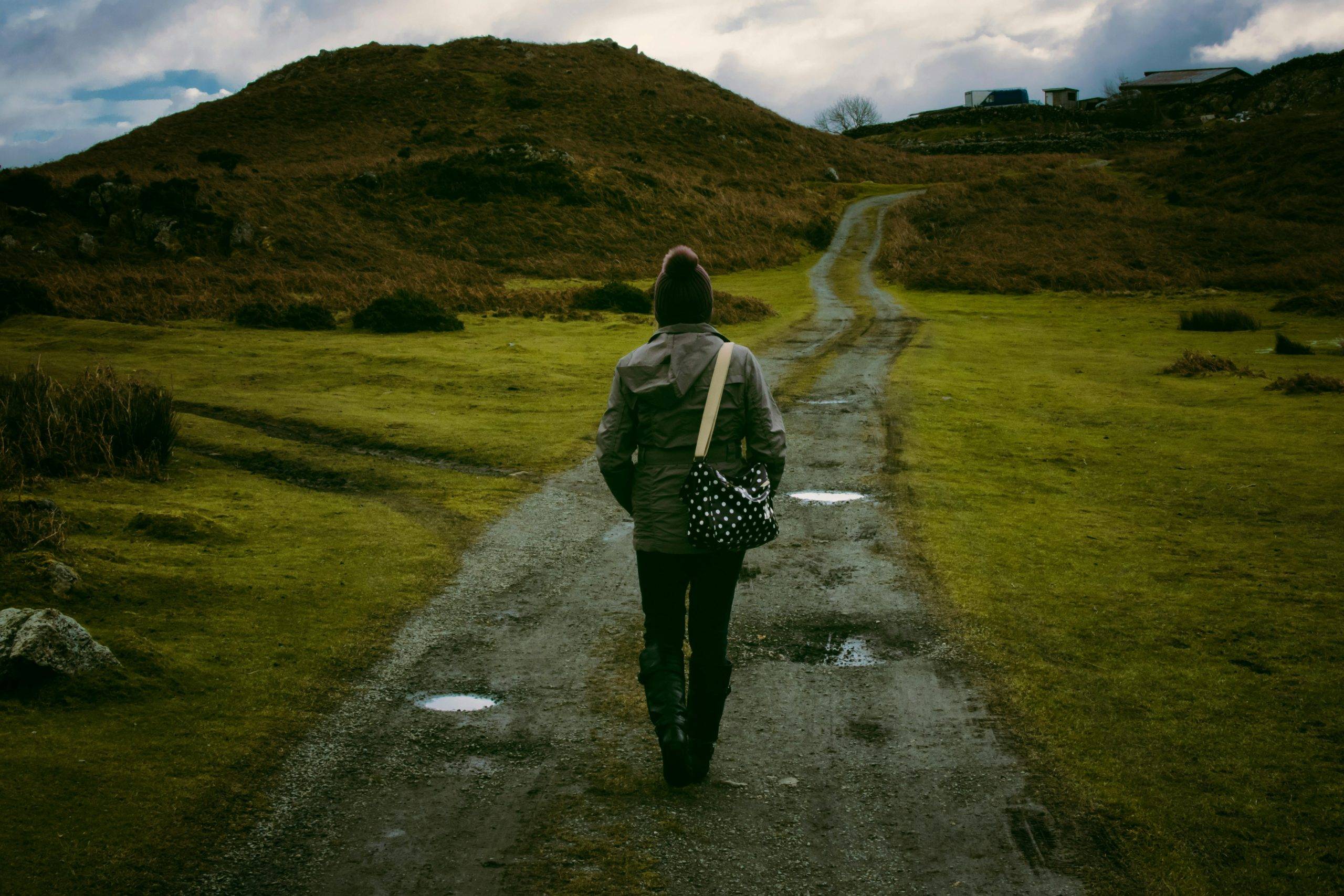 Trust vs loyalty in career decisions - A woman with her back to the camera looking forward into a path that goes through mountains.